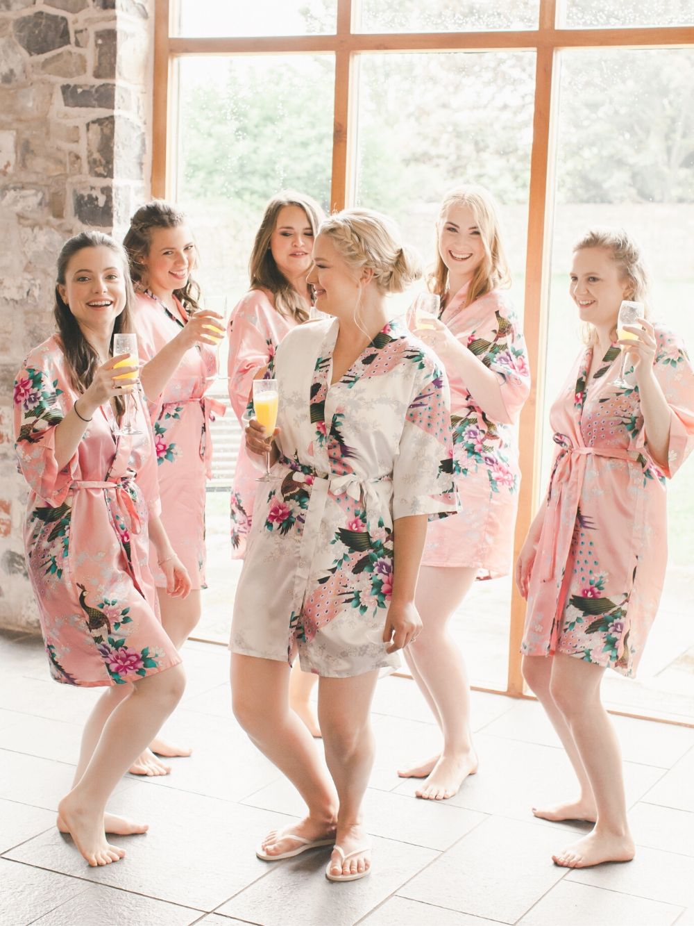 Bride and her bridesmaids getting ready on the wedding day in their pink silk kimonos
