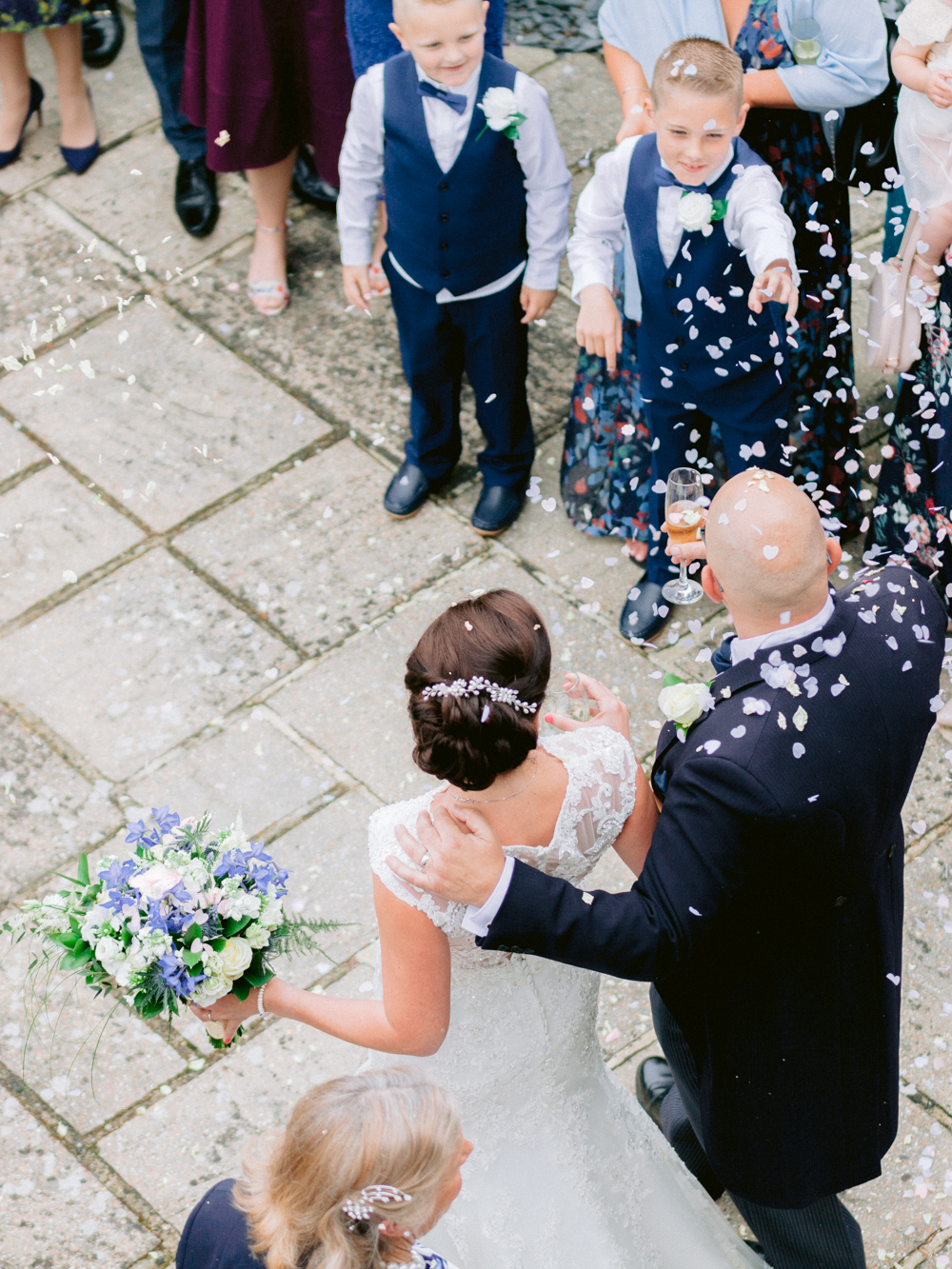 Family throw confetti at the bride and Groom as they step outside the balcony door of Gorse Hill Manor