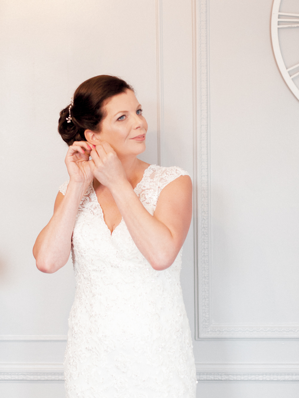 Bride puts her earring on in the bridal suite of Gorse Hill Manor