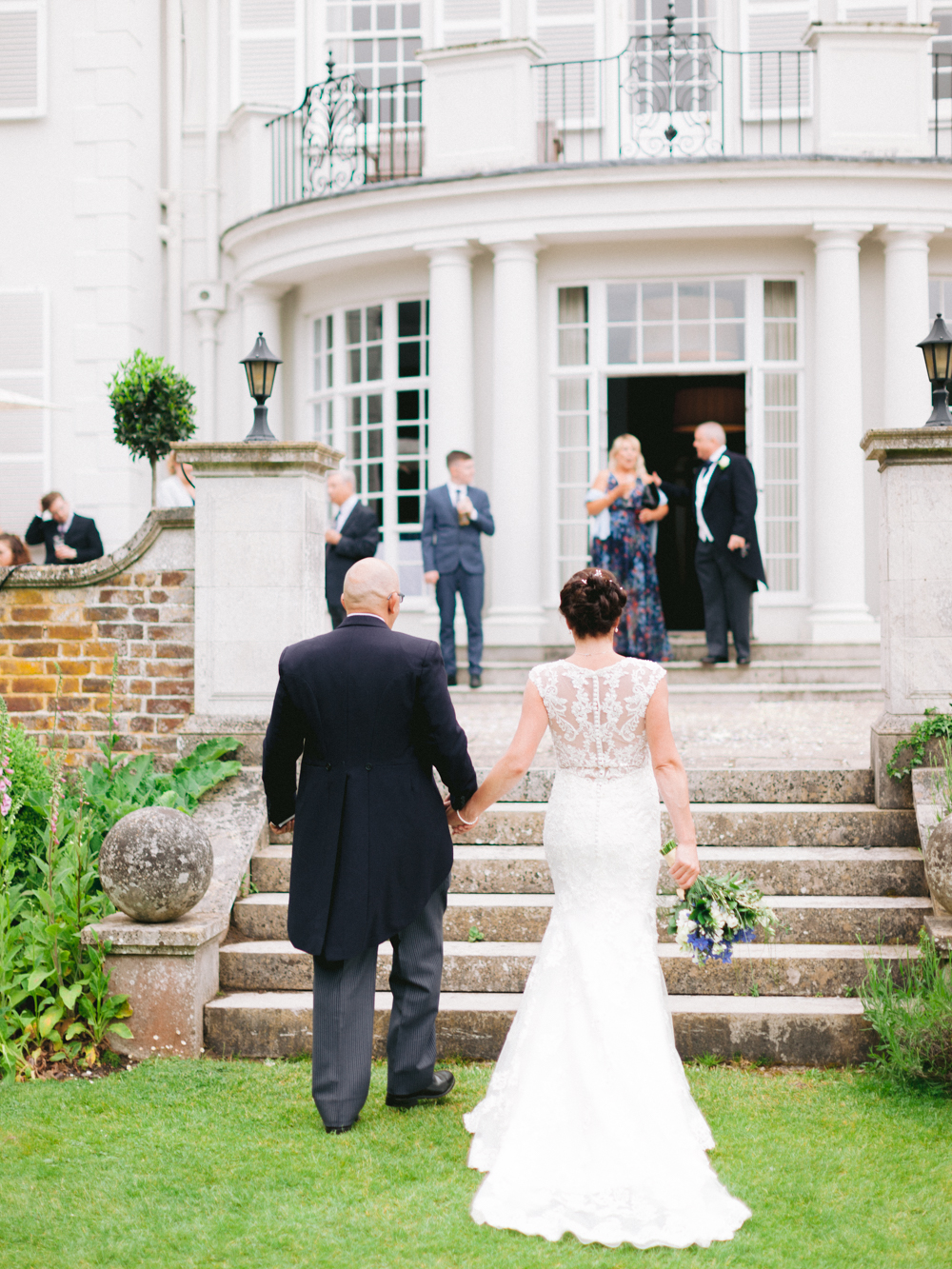 Bride and Groom hold hands after the ceremony and walk across the lawn of Gorse Hill Manor