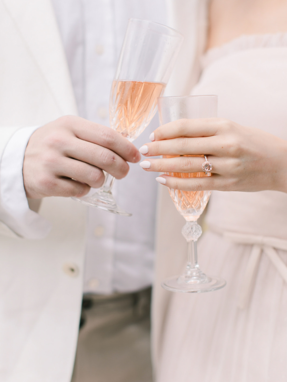 pink champagne in crystal glasses are held in celebration after the proposal at Eastington park