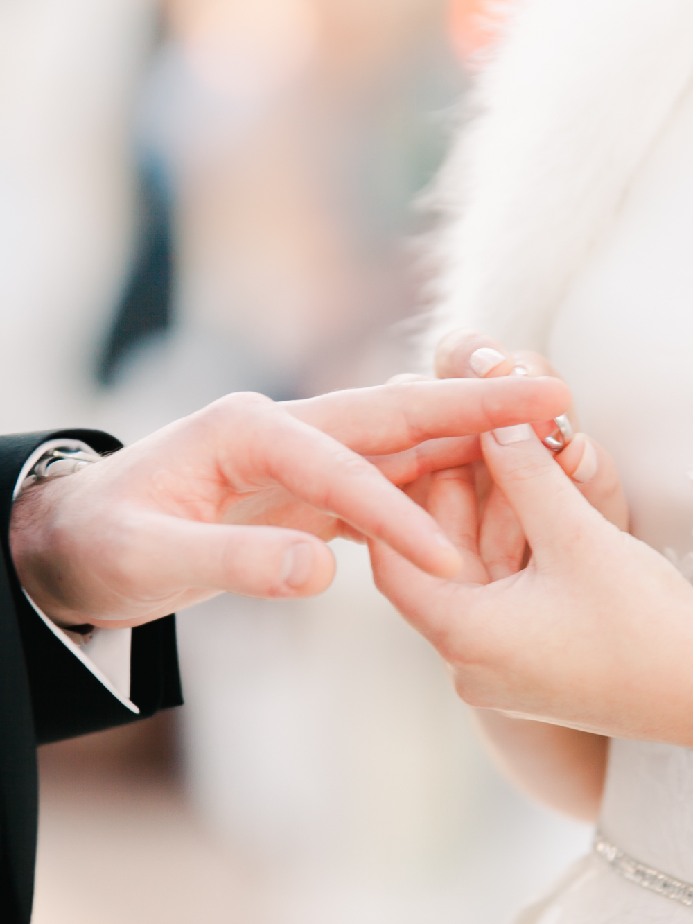The bride places wedding band on grooms finger