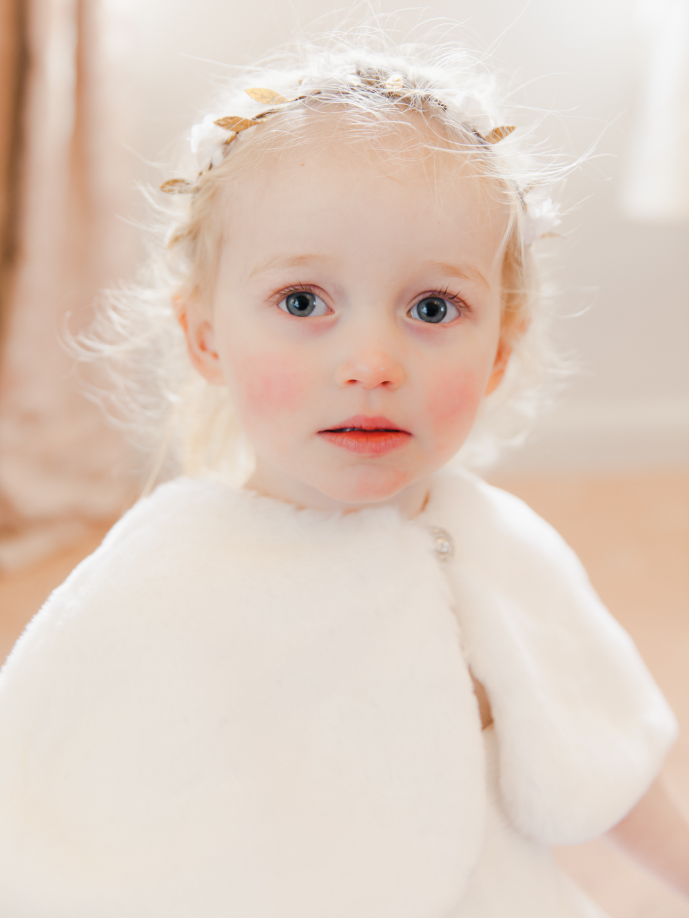 Little flower girl wearing white fur stole for the winter wedding at St Audries Park