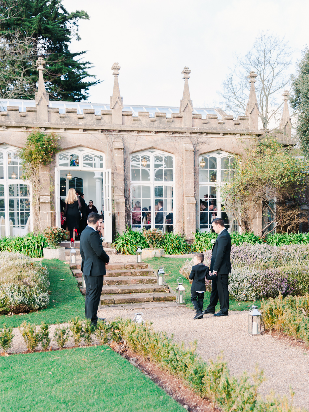 Wedding guests wait outside the orangery in the garden of St Audries Park
