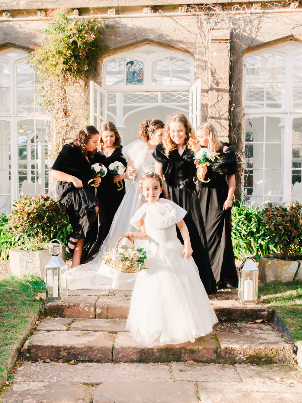 The bridal party stand outside the orangery in the winter wedding sunshine of the country house 