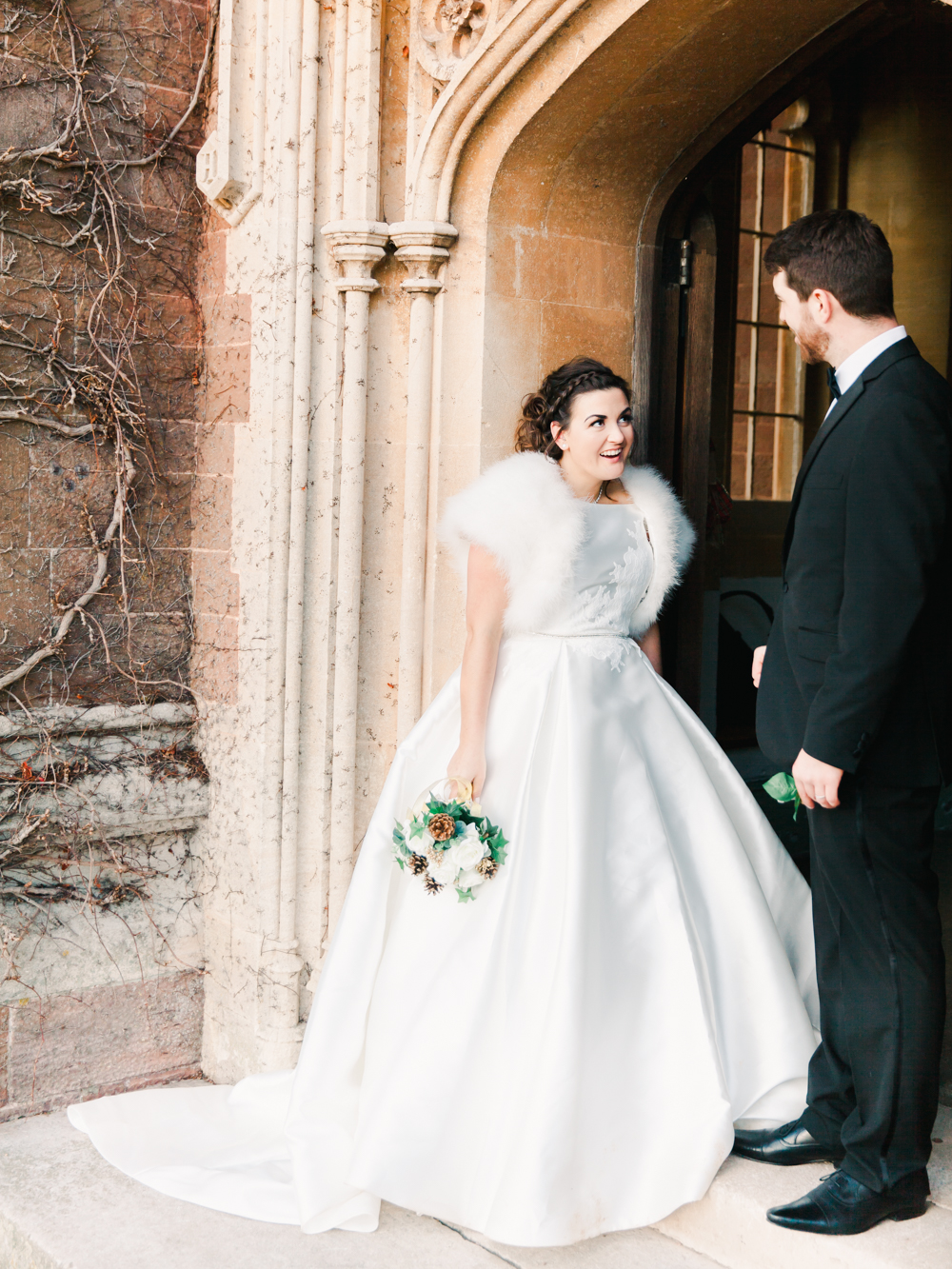 Bride and Groom stand in the door way of country manor house for their winter wedding portraits