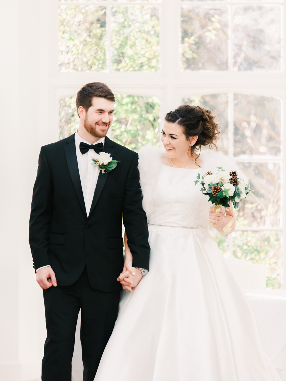 Bride wearing winter wedding dress and Groom wearing black tuxedo walk down the aisle smiling in Somerset Orangery