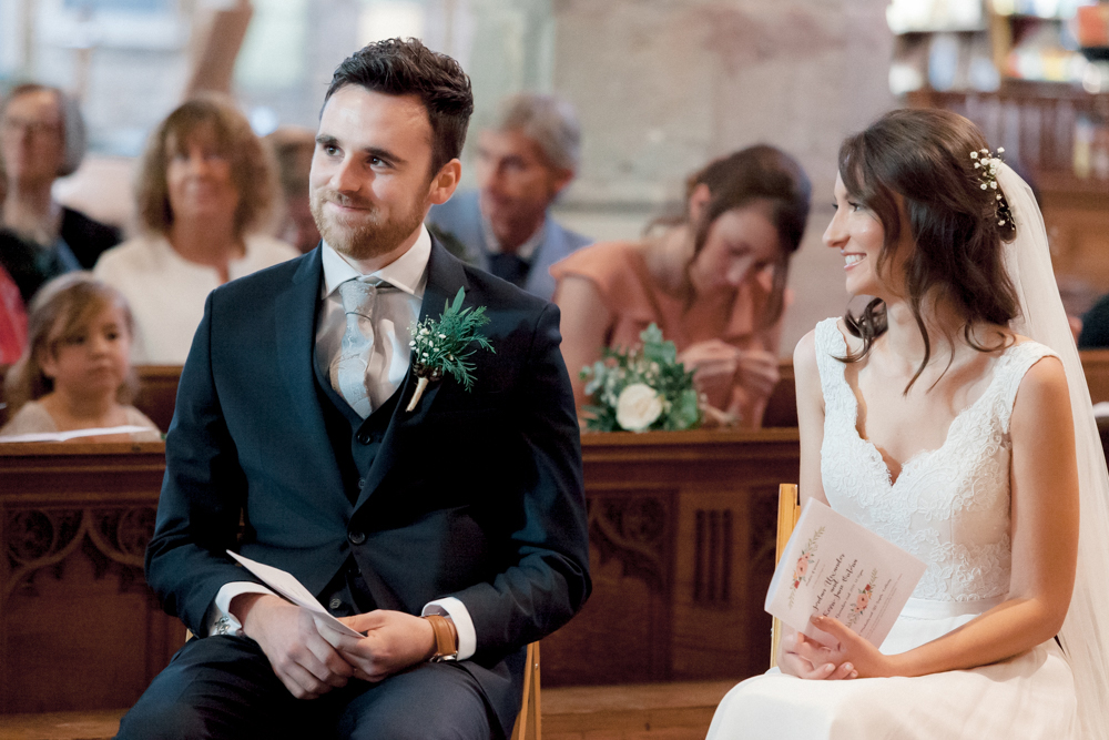 Romantic image of bride and groom looking at each other in Cotswolds church wedding