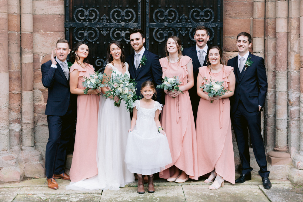 Group portraits in front of the church doors at a romantic Cotswolds wedding