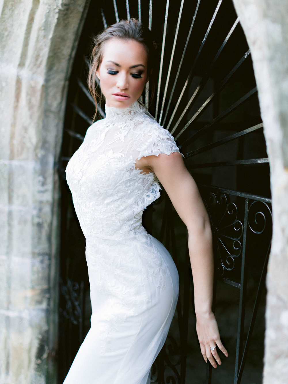 Model stands against chapel wearing lace style wedding dress