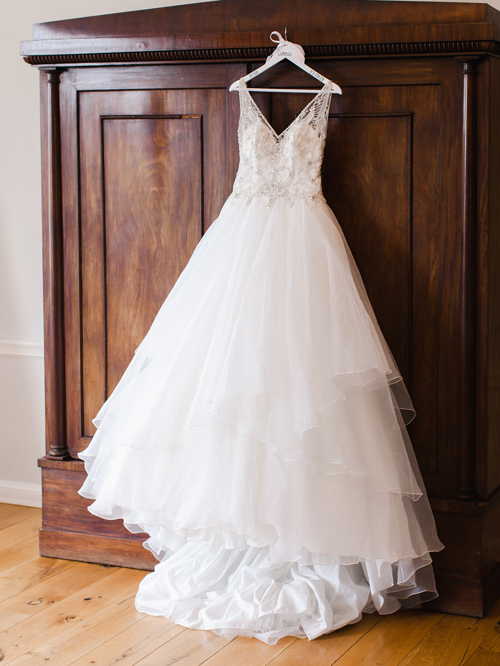 Morilee wedding dress hanging from the vintage wardrobe in the bridal suite at Rockbeare Manor
