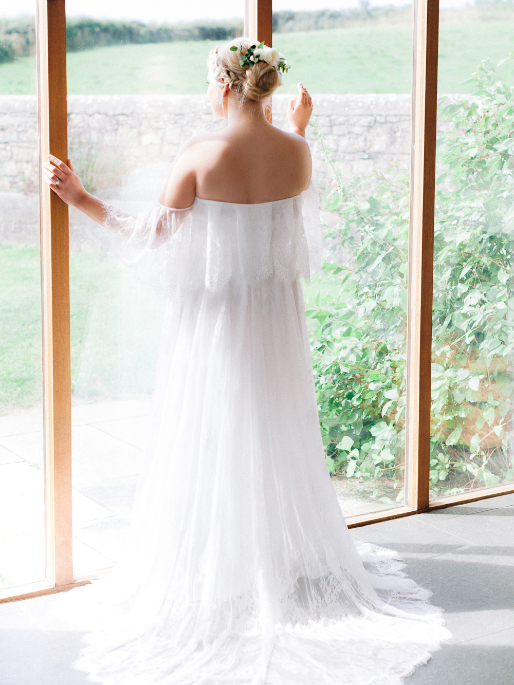 Bride stands in the window of Rosedew Farm on her summer wedding day