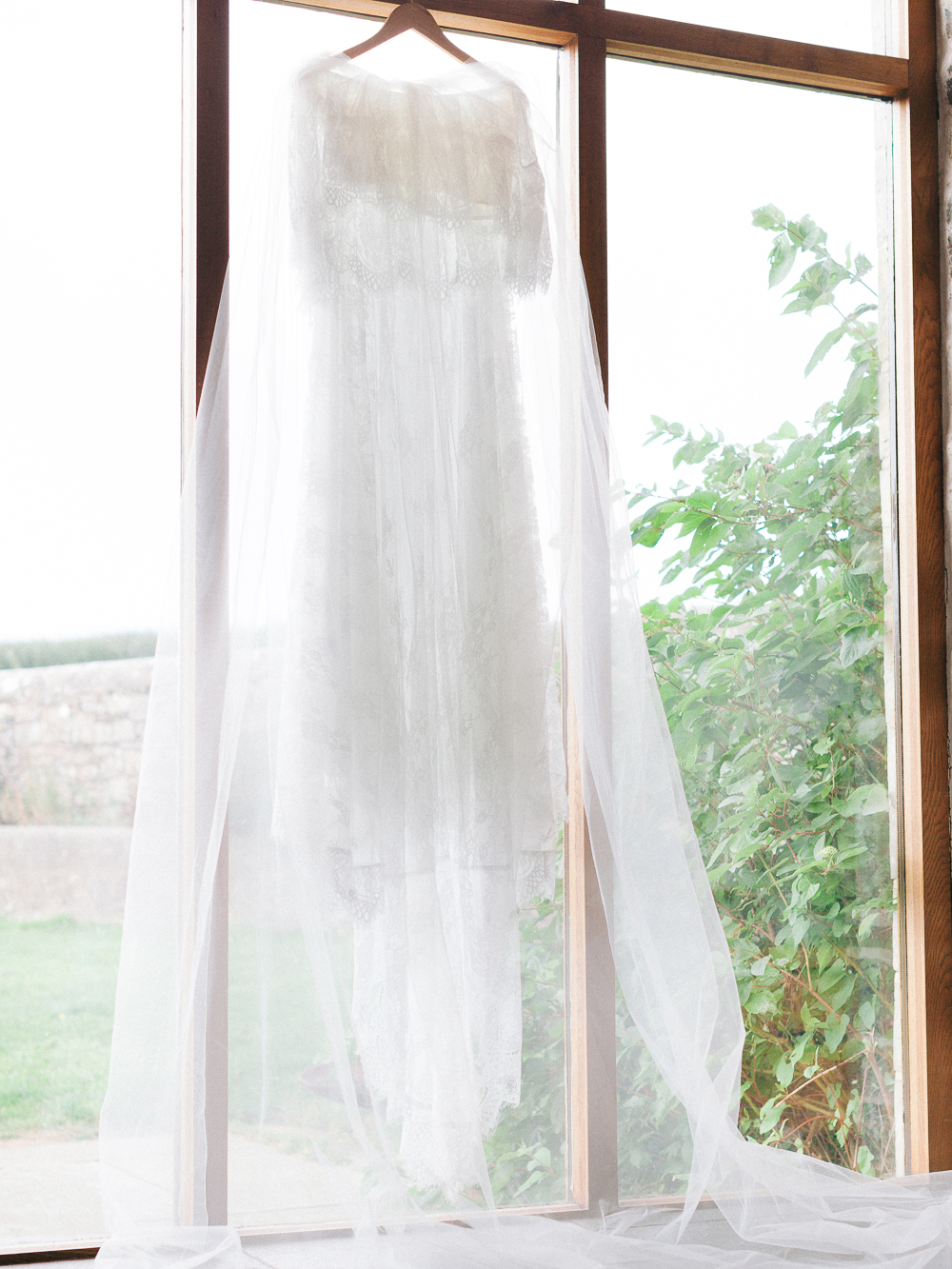Chantilly lace wedding dress hanging in the window of Rosedew Farm