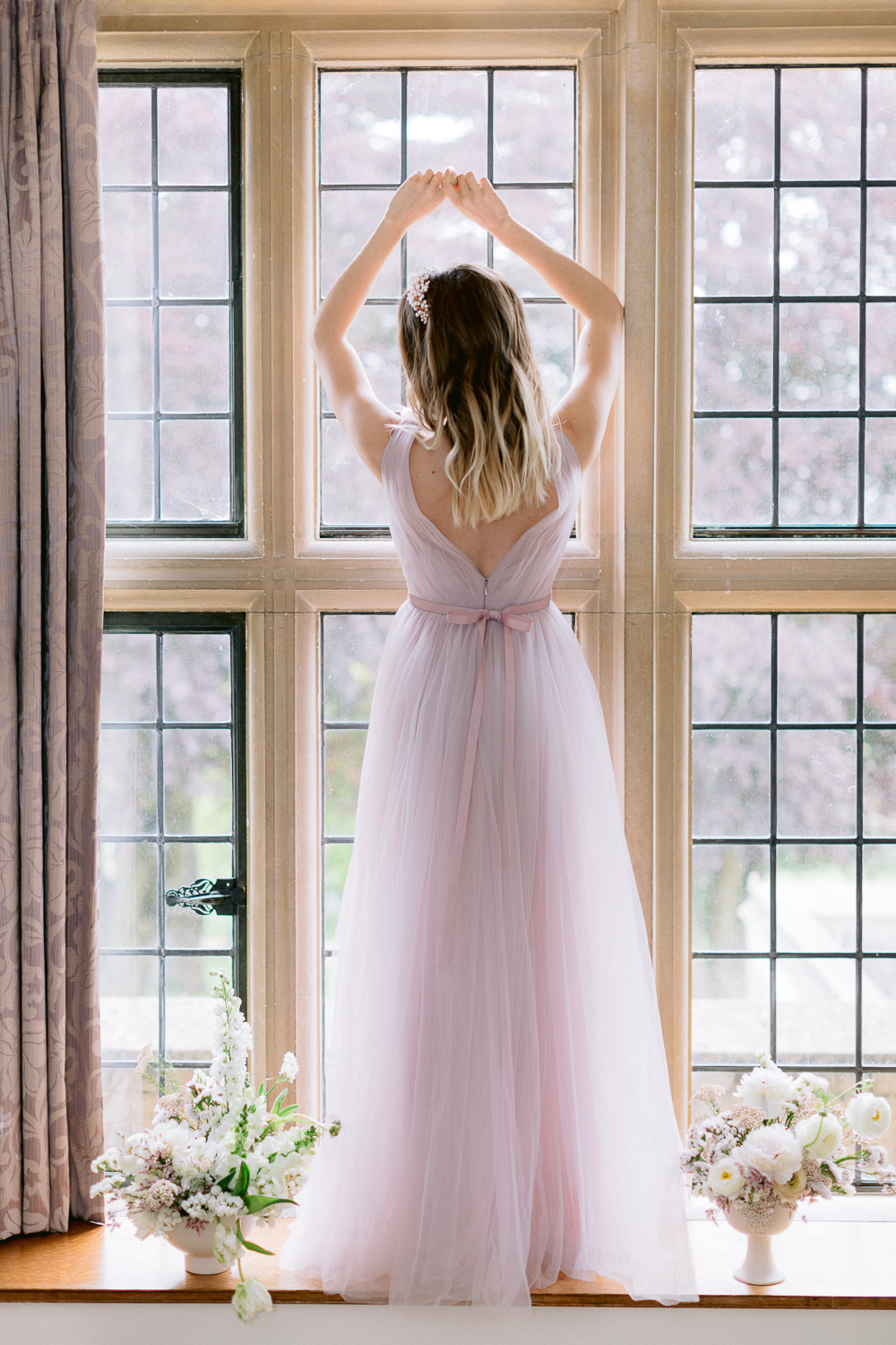 Lilac tulle bridesmaid dress in window of fairytale wedding venue 