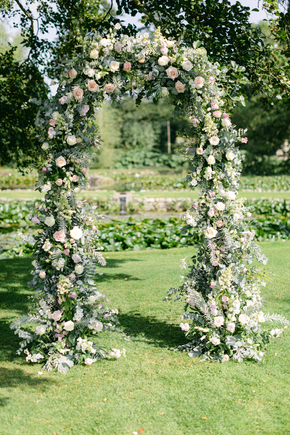 A light pink rose floral arch stands in the gardens of romantic brinsop court