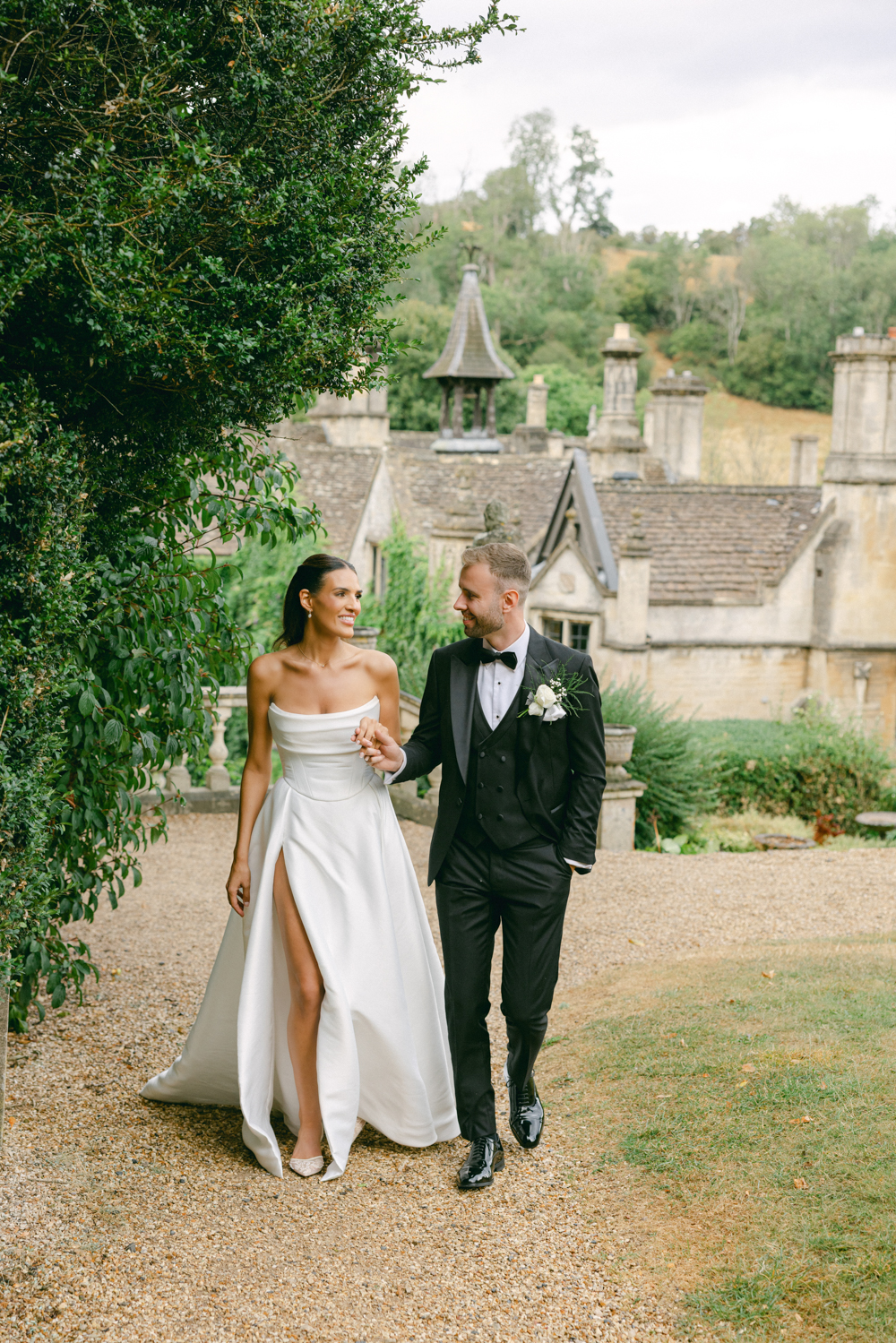 Bride and Groom walk through the Cotswolds Manor House